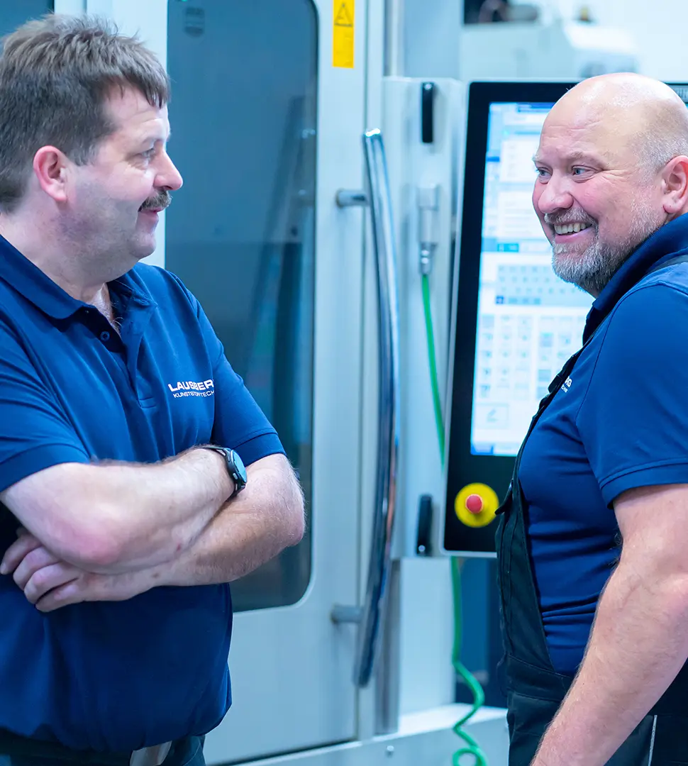 Zwei Mitarbeiter stehen an einer Maschine